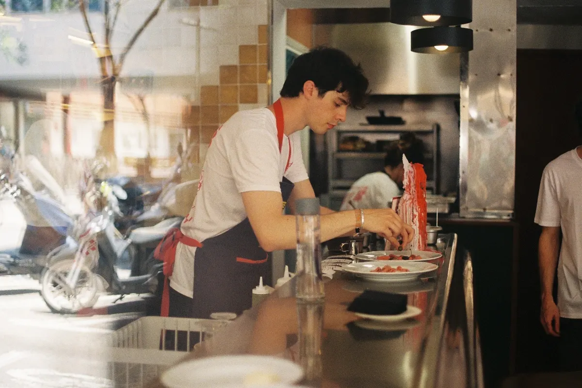 Andrea plating pasta at a restaurant counter in Barcelona